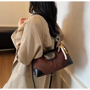 Detailed shot of retro suede bag with brown contrast leather and colorful beaded charm