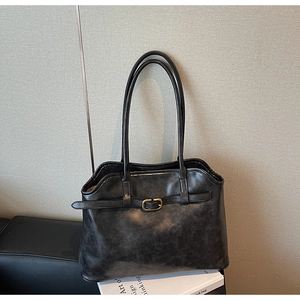 Détail d'un cabas noir vintage avec boucle dorée décorative et fines bretelles d'épaule