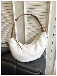 Close-up of fluffy white faux fur hobo bag featuring adjustable brown leather shoulder strap