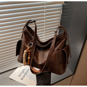 Detail of vintage brown leather bucket bag with bohemian beads and textured side pocket