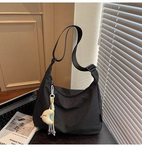Détail du sac hobo en toile à carreaux avec large sangle et breloque lune en peluche