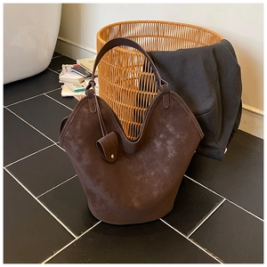 Close-up of brown suede bucket tote bag with matching hanging pouch in a home setting