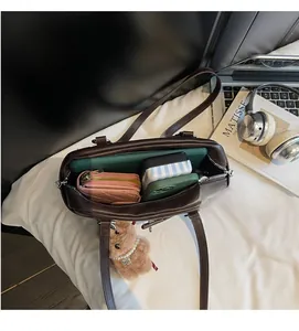 Detail showing the spacious interior of a dark brown leather Boston bag with belongings