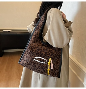 Detail of leopard print suede hobo bag featuring colorful tassel and logo brand name