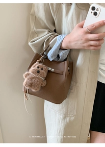 Brown litchi leather bucket bag with silver clasp and plush puppy charm on handle