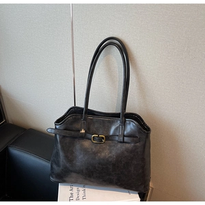 Gros plan sur un sac cabas noir rétro avec texture en cuir et boucle dorée élégante