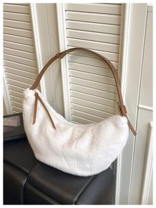 Detail of plush white half-moon bag with adjustable brown leather strap and tassel