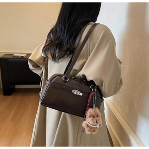 Detail of vintage brown leather boston bag with metal lock and cute teddy bear charm
