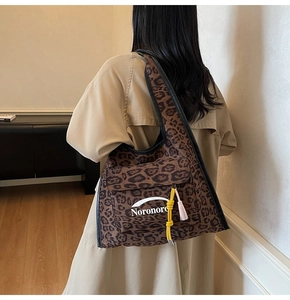 Detail of suede leopard print hobo bag with front flap pocket and decorative tassels
