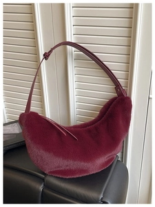 Macro shot of fluffy burgundy faux fur texture and adjustable leather strap on crescent bag