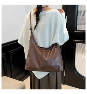 Detail of vintage dark brown Hobo bag with natural leather texture worn as a crossbody