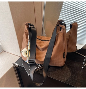 Détail du sac hobo à carreaux marron avec large bandoulière et breloque lune en peluche