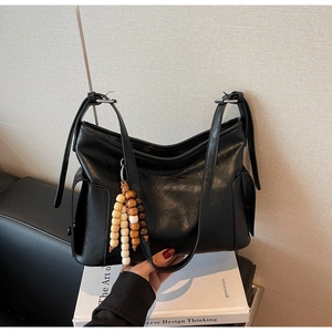 Close-up of retro black tote with glossy leather texture and wooden bead tassel