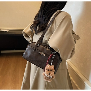 Detailed view of deep brown vintage Boston bag with plush charm on a shoulder strap