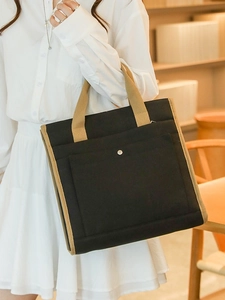 Minimalist black canvas tote bag with khaki straps and front pocket for daily commute