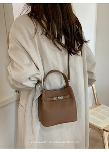 Rear view of a model wearing a brown lychee leather bucket bag with silver metal buckle