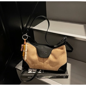 Detail of khaki suede and black leather dumpling bag with colorful beaded charm on a step
