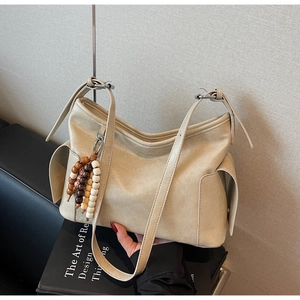 Detail of cream faux leather hobo bag featuring decorative multi-color wooden beads
