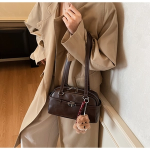 Detail of dark brown vintage underarm bag with silver buckle and plush puppy charm