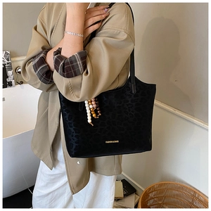 Détail du sac cabas noir à motif léopard avec pendentif en perles et lettrage doré