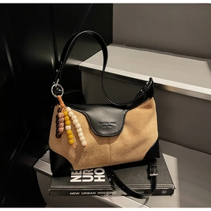 Detail of color-block leather dumpling bag with beaded charm and embossed logo