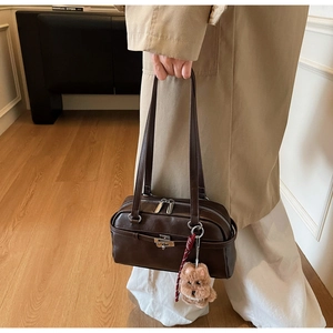 Detail of vintage brown leather handbag with metal buckle and plush puppy charm