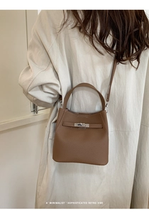 Rear view of brown litchi leather bucket bag worn with a casual trench coat
