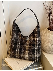 Sac fourre-tout en laine à carreaux avec anses en cuir dans un décor de voyage de luxe