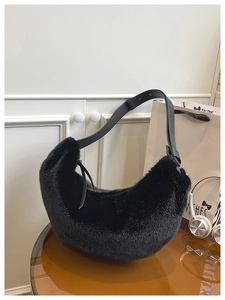 Macro shot of fluffy black faux fur texture and leather strap on hobo shoulder bag