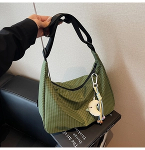Détail du sac à main en toile à carreaux verts avec un joli accessoire en peluche lune