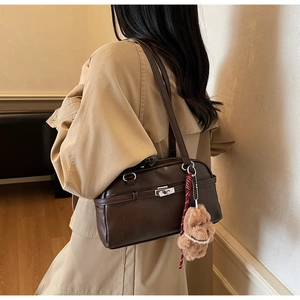 Detail view of dark brown retro leather underarm bag on a beige trench coat