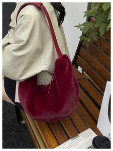 Detail view of the large burgundy faux fur crescent shoulder bag worn on a casual outing