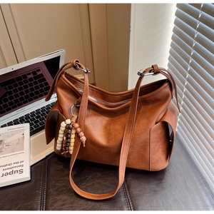 Macro detail of brown retro crossbody bucket bag with wooden bead tassel and side pockets