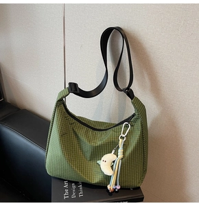 Détail du sac bandoulière en toile à carreaux verts avec peluche lune et pompon perlé