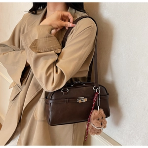 Detail of dark brown shoulder bag featuring silver clasp and cute puppy charm accessory