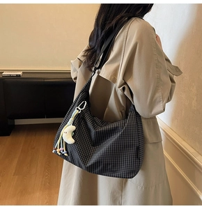 Détail du sac en toile à carreaux avec pendentif lune et large bandoulière noire