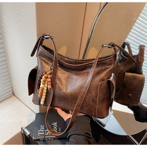 Macro shot of vintage brown leather bucket bag featuring a colorful wooden bead charm detail