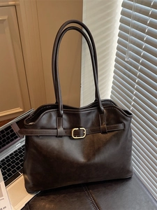 Grand sac cabas marron foncé en cuir avec boucle dorée sur un bureau professionnel