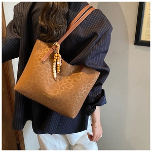 Détail d'un grand sac cabas à imprimé léopard avec pompon perlé et fine bandoulière en cuir