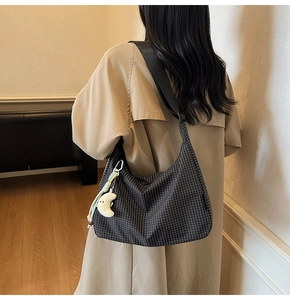 Détail du sac hobo en toile à carreaux avec pendentif lune en peluche et bandoulière