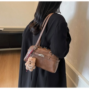 Brown vintage leather shoulder bag with a plush puppy charm and silver twist lock detail