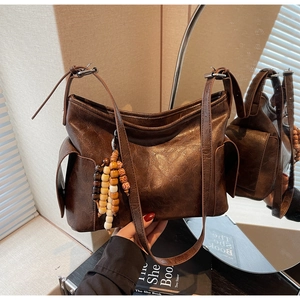 Detail view of brown vintage bucket bag with unique wooden bead tassel and side pocket