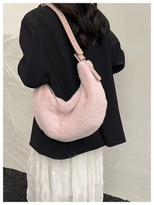 Pink plush dumpling bag with adjustable strap shown from a model's side view