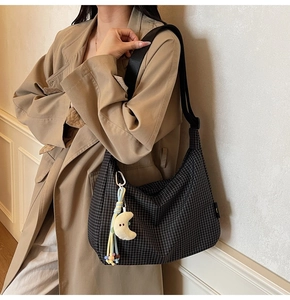 Détail du sac hobo à carreaux noirs et blancs avec un pendentif lune en peluche