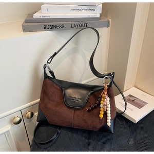 Detail of two-tone crossbody bag with brown suede, black leather and beaded charms