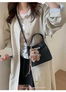 Litchi pattern leather bucket bag with silver twist lock and cute bear charm shown on model