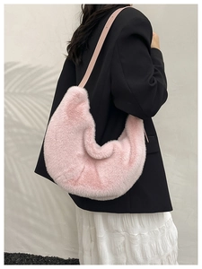 Detail of pink faux fur crescent bag with matching leather strap on model's shoulder