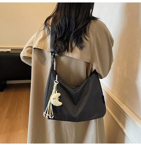 Détail du sac en toile à damier avec large bandoulière et breloque lune en peluche