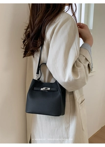 Detail of black lychee grain leather bucket bag with silver metal twist-lock and shoulder strap