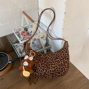 Detail of leopard print hobo bag with brown faux leather trim and cute plush bear charm